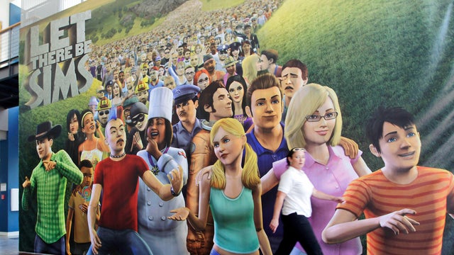 An employee passes a poster for The Sims 3 video game in the cafeteria of the Electronic Arts Inc. headquarters in Redwood City, California, July 20, 2010.